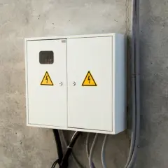 Biała skrzynka elektryczna z żółtymi symbolami ostrzegawczymi, gotowa do złożenia wniosku o przyłącze prądu.