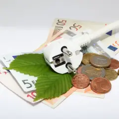 Wtyczka, liście i monety na banknotach euro symbolizują poszukiwanie, gdzie najtańszy prąd.