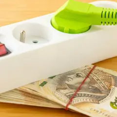 Przedłużacz z wtyczką i włącznikiem na stosie banknotów 200 zł. Oszczędzanie na tańszy prąd dla gospodarstw domowych.