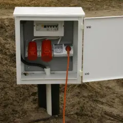 Skrzynka elektryczna z zabezpieczeniami i gniazdami, gotowa do złożenia wniosku o przyłączenie prądu do działki.