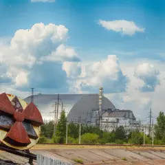 Rdzawe koło symbolizujące zagrożenie promieniotwórczością na tle sarkofagu Czarnobylskiej Elektrowni. Kiedy Czarnobyl będzie bezpieczny?