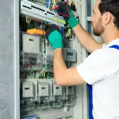 Elektryk sprawdza liczniki, by zapewnić obniżkę za prąd.