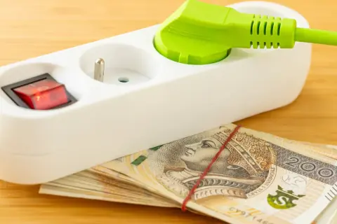 Przedłużacz z wtyczką i włącznikiem na stosie banknotów 200 zł. Oszczędzanie na tańszy prąd dla gospodarstw domowych.