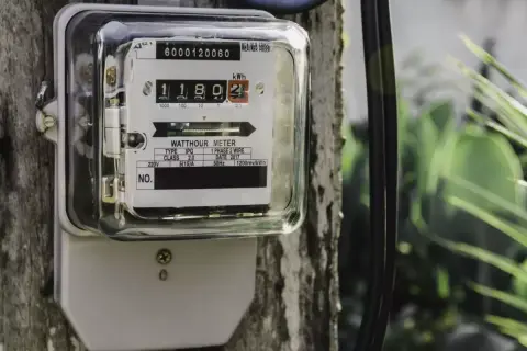 Podłączenie licznika prądu do drewnianego słupa. Urządzenie pokazuje zużycie energii elektrycznej.