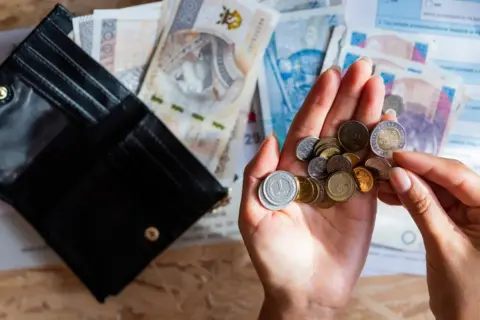 Dłonie liczą monety i banknoty, zastanawiając się nad cenami prądu w taryfie G11.