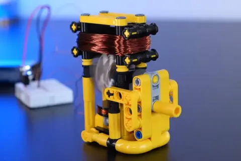 Model z klocków pokazuje, jak wytworzyć prąd z magnesu. Wirująca cewka miedziana nad magnesem generuje energię.