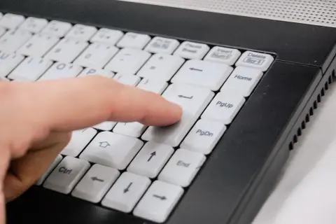 Palec naciska klawisz Enter na klawiaturze laptopa, symbolizując łatwy sposób, jak kupić prąd przez internet.
