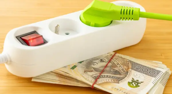 Przedłużacz z wtyczką i włącznikiem na stosie banknotów 200 zł. Oszczędzanie na tańszy prąd dla gospodarstw domowych.