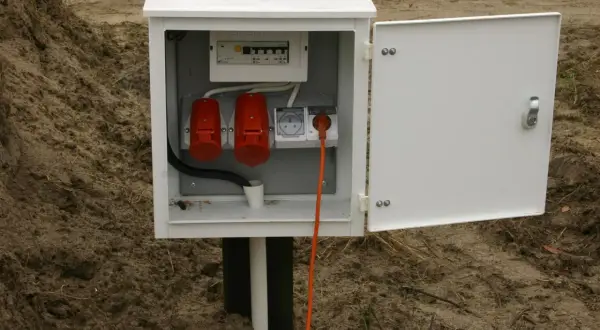 Skrzynka elektryczna z zabezpieczeniami i gniazdami, gotowa do złożenia wniosku o przyłączenie prądu do działki.